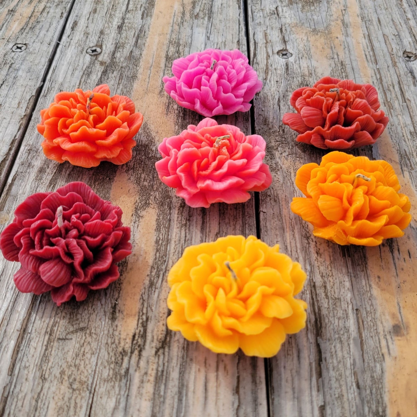 Seven handmade flower votive candles in a variety of colors.