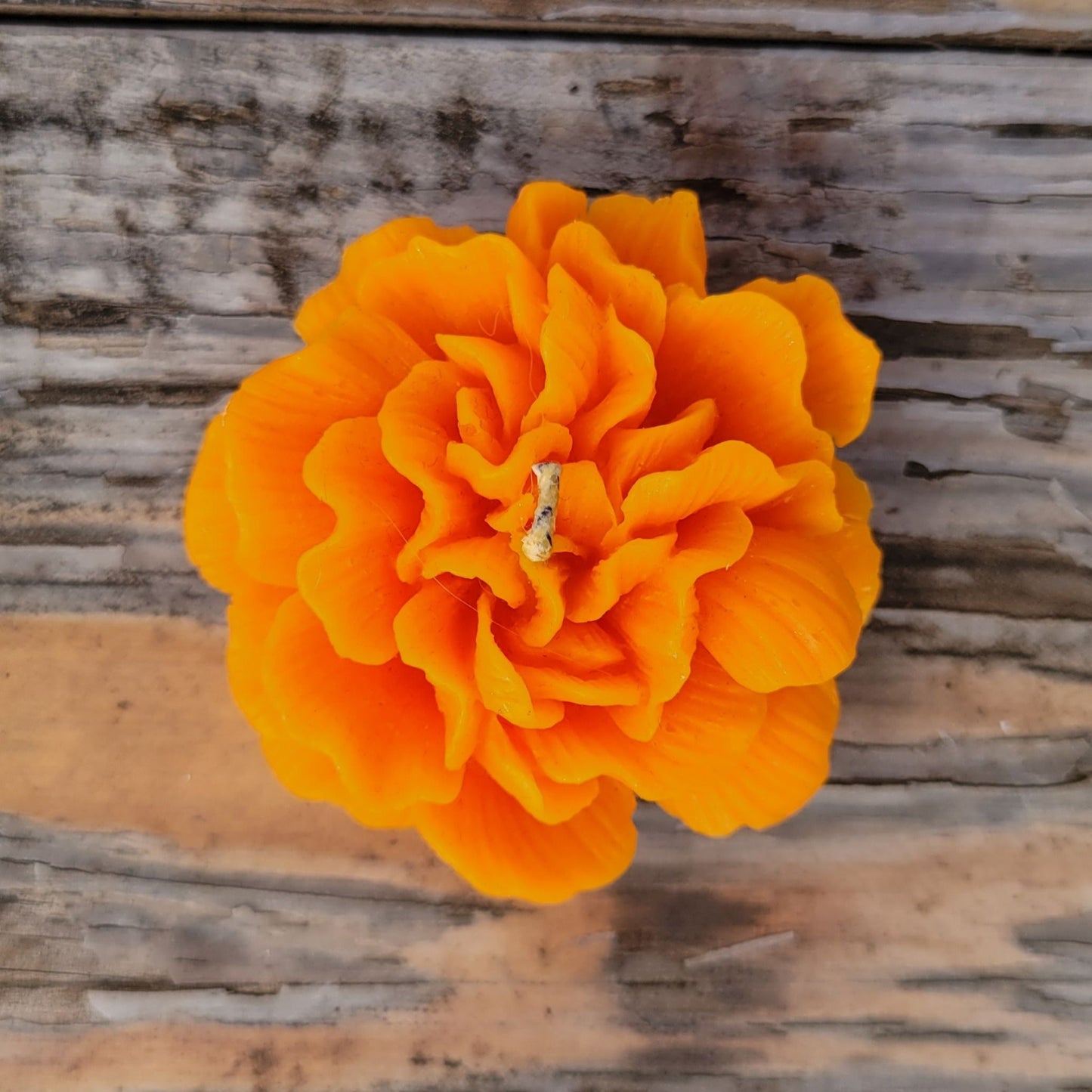 A handmade orange flower votive candle.
