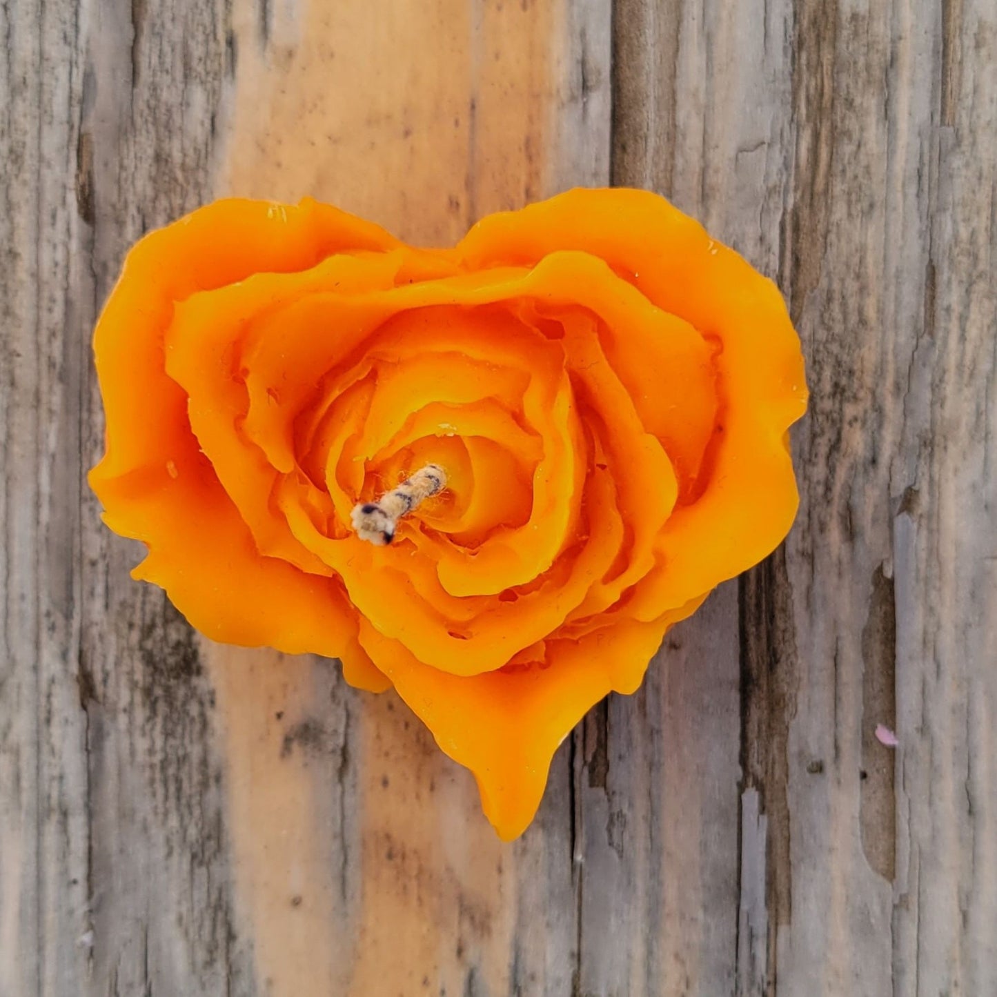 A handmade orange heart shaped flower votive candle.
