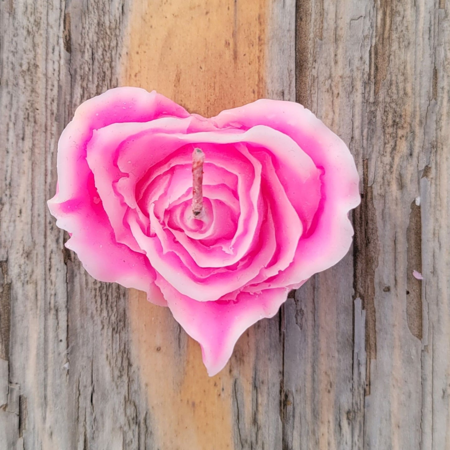 A handmade heart shaped flower votive candle in pink with white edges.