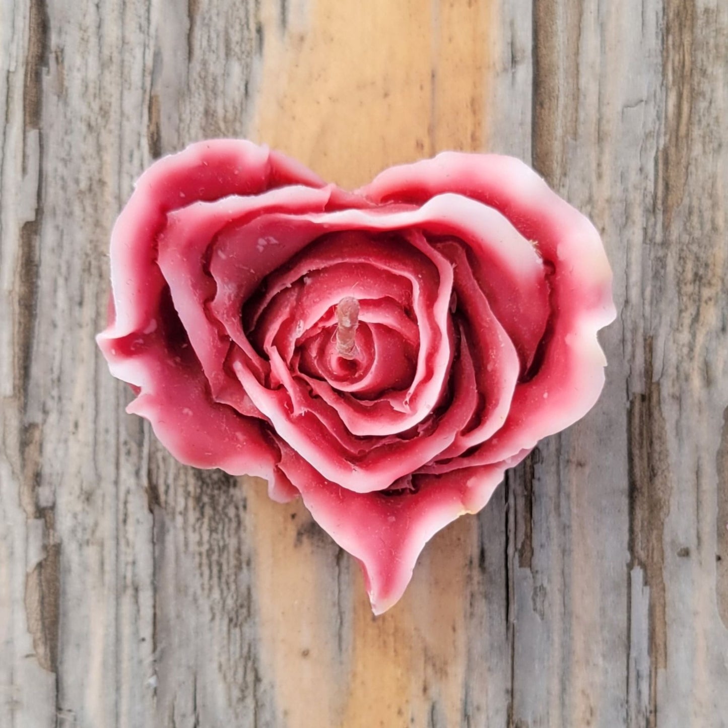A handmade heart shaped flower votive candle in dark red with white edges.