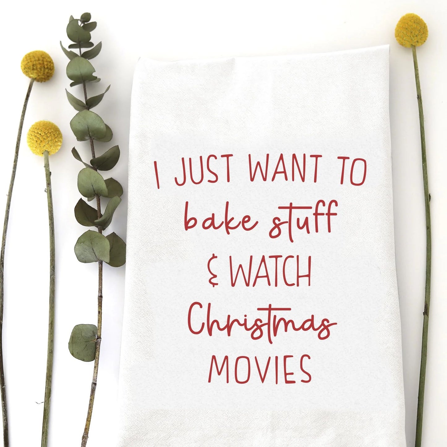 A holiday tea towel with the words "I just want to bake stuff & watch Christmas movies" printed on it.
