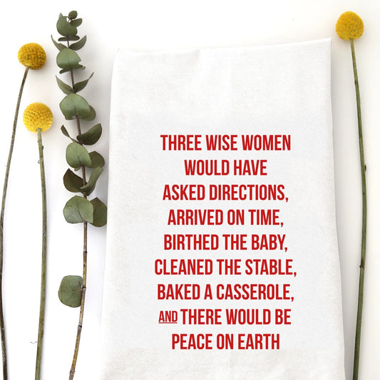 A holiday tea towel with the words "Three wise women would have asked directions, arrived on time, birthed the baby, cleaned the stable, baked a casserole, and there would be peace on earth" printed on it.