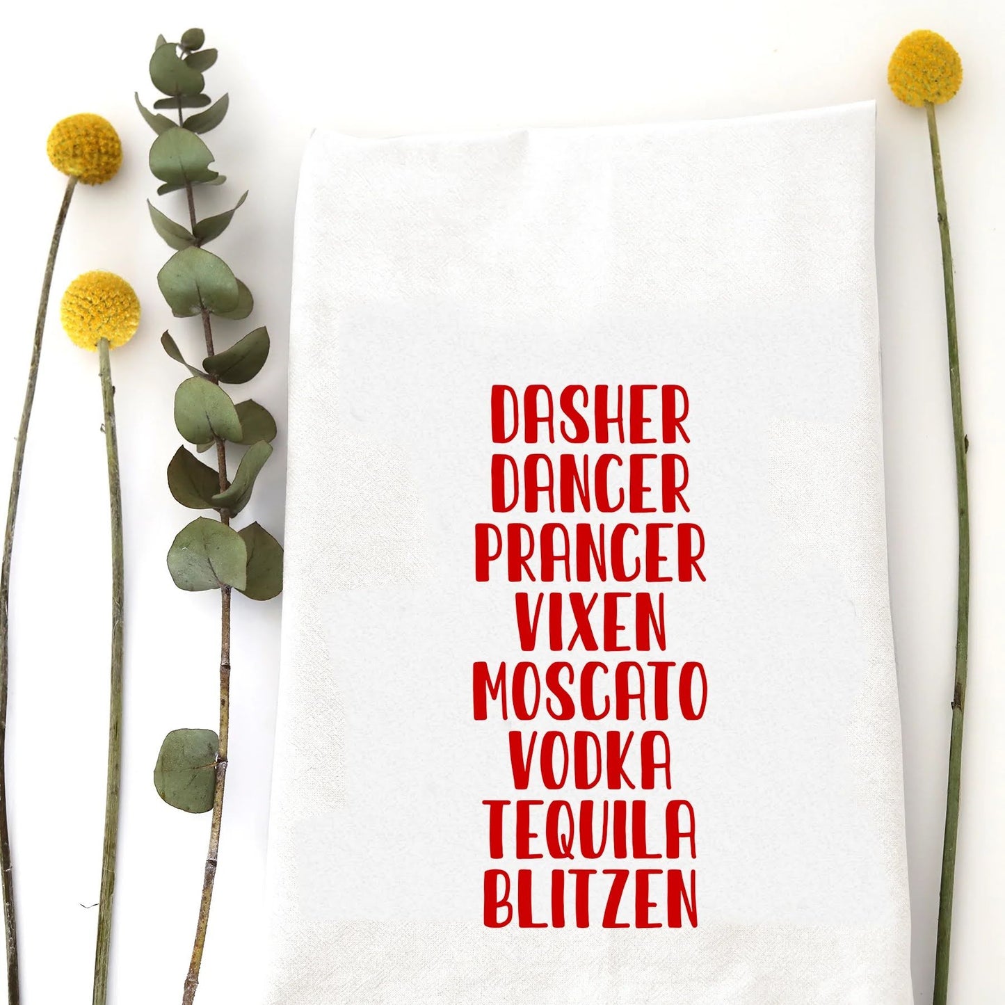 A holiday tea towel with the words "Dasher, Dancer, Prancer, Vixen, Moscato, Vodka, Tequila, Blitzen" printed on it.