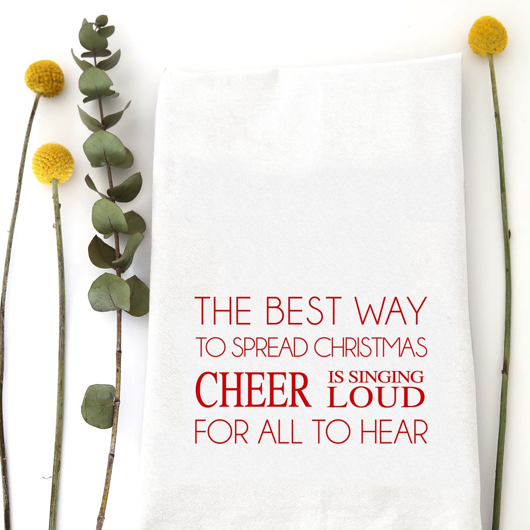 A holiday tea towel with the words "The best way to spread Christmas cheer is singing loud for all to hear" printed on it.